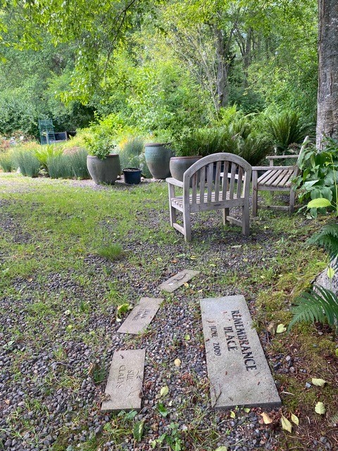 Memorial stones on path near sitting area in garden.