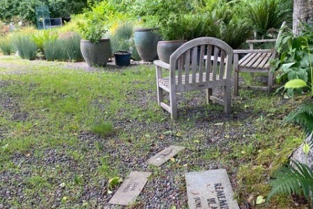 Memorial stones on path near sitting area in garden.