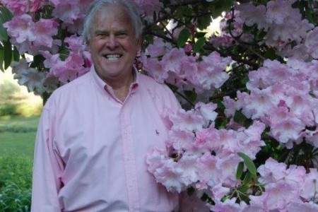 Patrick standing next to a rhododendron in full bloom.